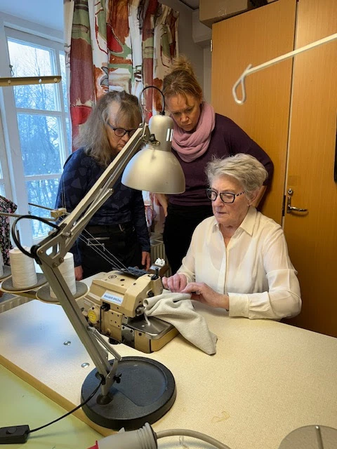 Elever och textillärare vid industrimaskin overlock